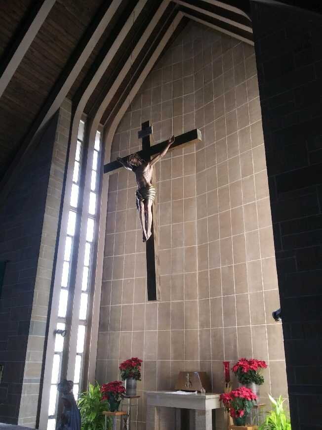 A large cross is hanging from the ceiling of a church.