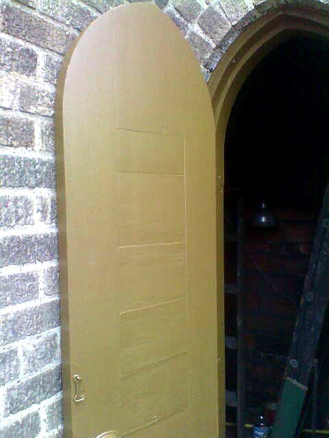 A wooden door is open on a brick wall.