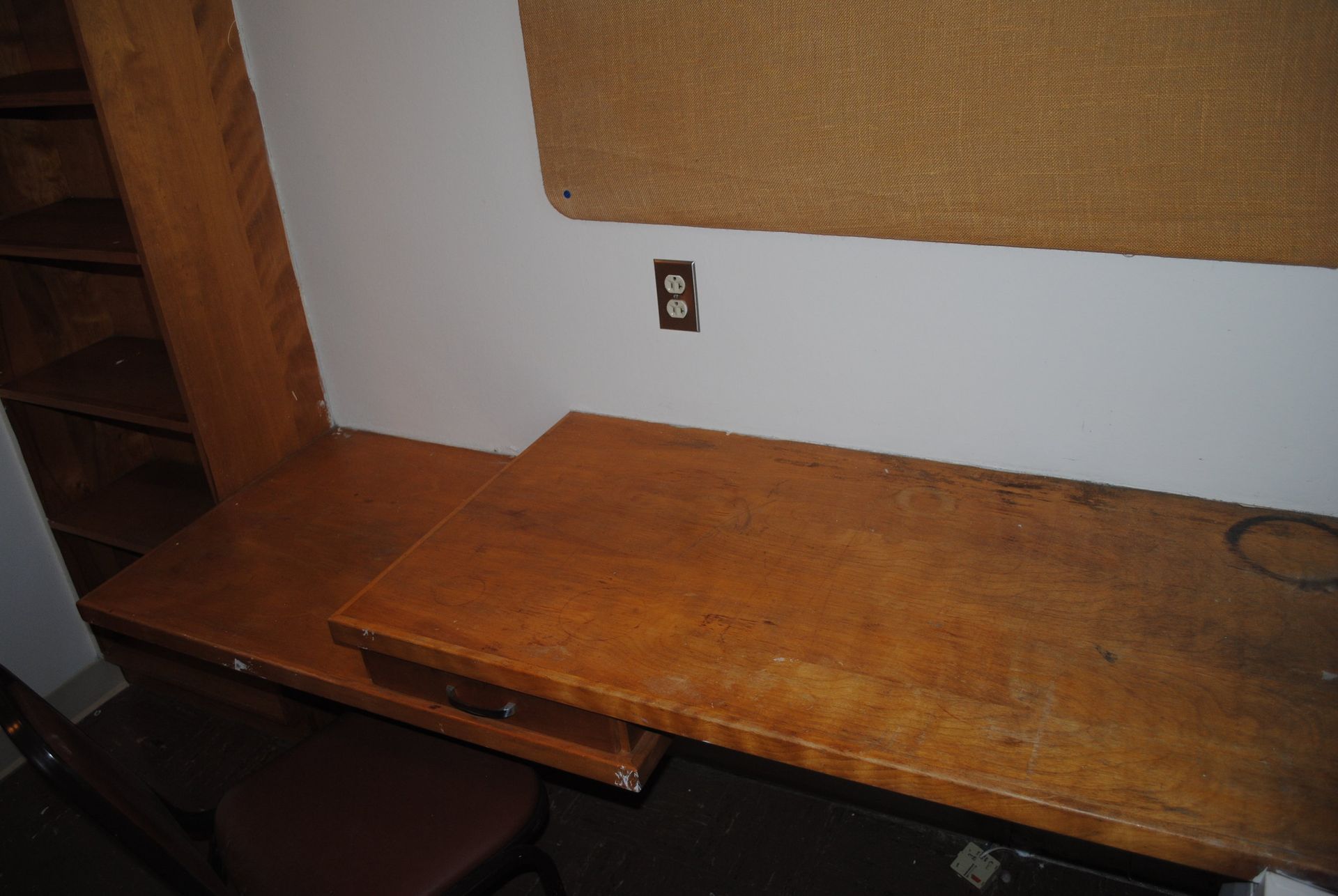 A wooden desk with a drawer underneath it in a room.