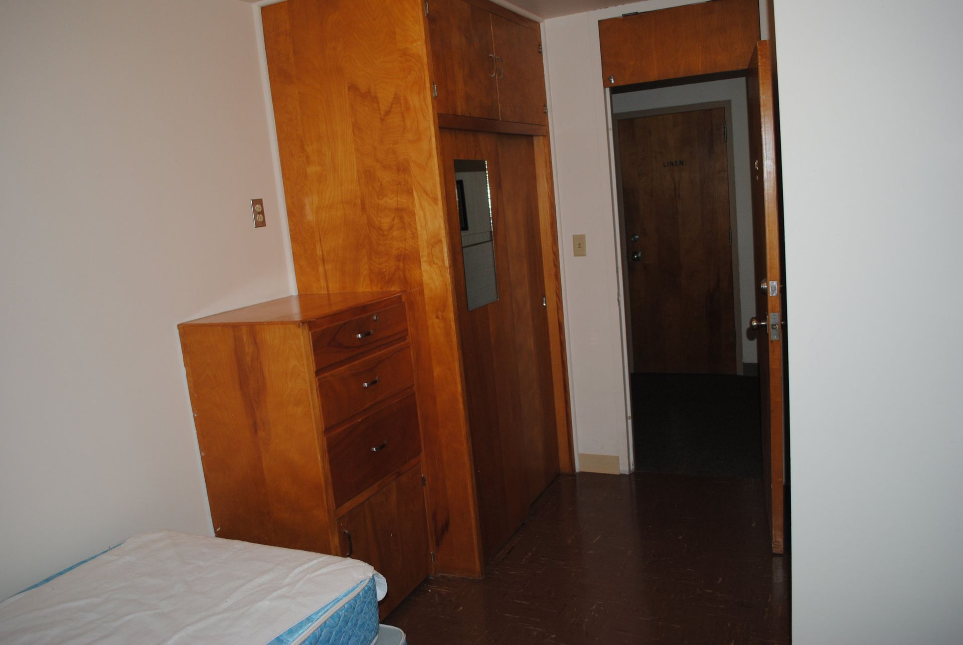 A bedroom with a bed , dresser , and door.