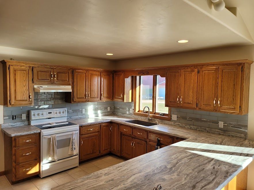 A kitchen with wooden cabinets , granite counter tops , a stove and a sink.