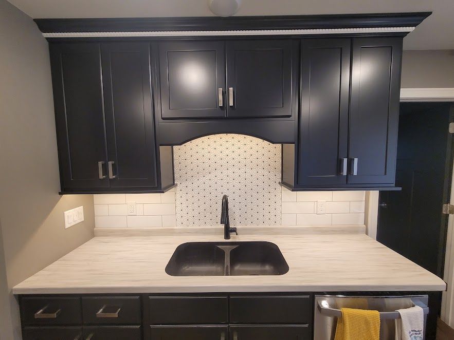 A kitchen with black cabinets and a sink.