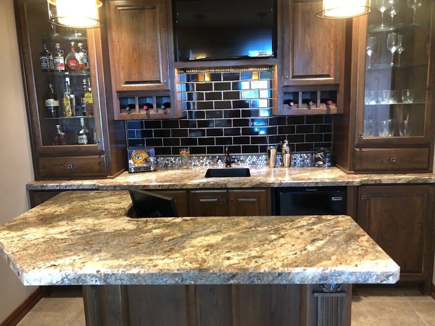 A kitchen with a large granite counter top and wooden cabinets.