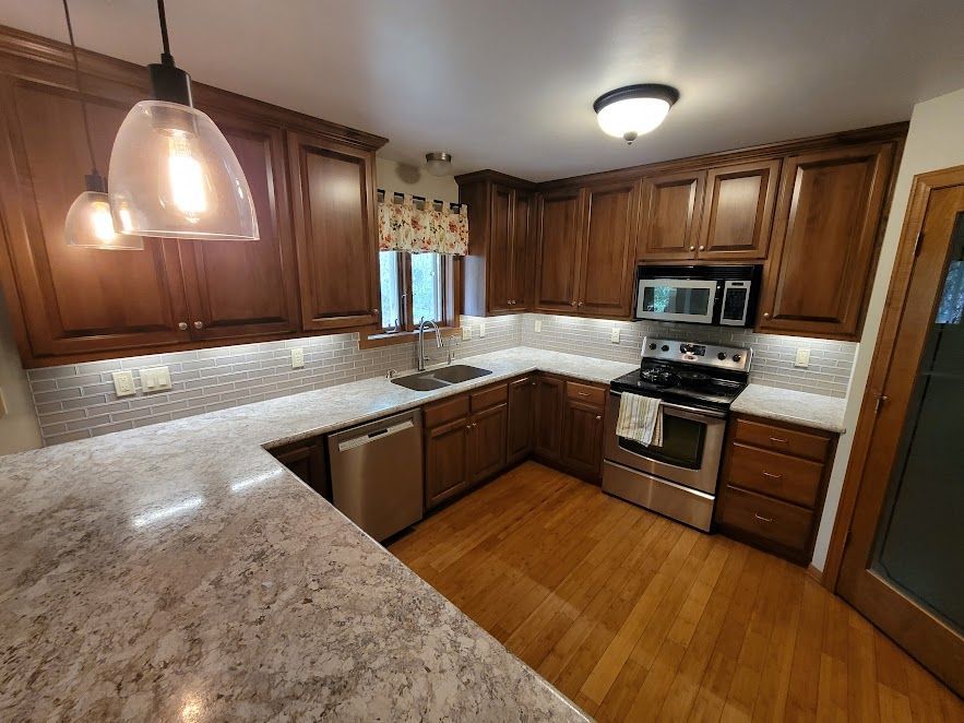 A kitchen with wooden cabinets , granite counter tops , stainless steel appliances and a stove.