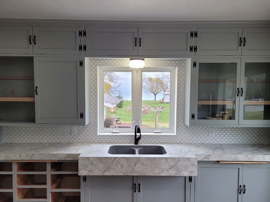A kitchen with a sink and a window with a view of a field