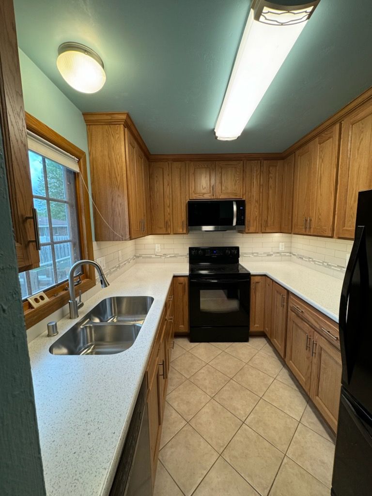 A kitchen with a sink , stove , microwave , and refrigerator.