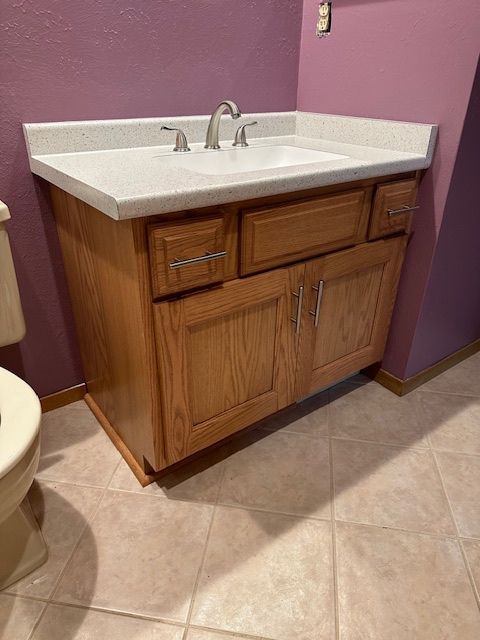 A bathroom with a sink , toilet and purple walls.