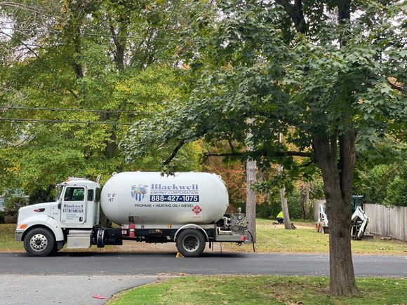 White water truck parked on a tree-lined street in a residential neighborhood.