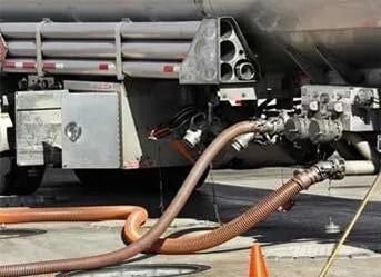 Fire truck with hoses on the ground, spraying water near an open vehicle compartment.