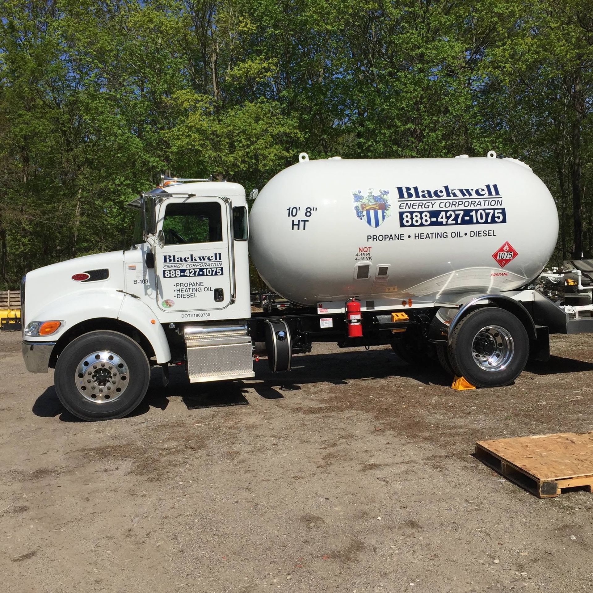 White Blackwell-branded tanker truck parked outdoors on a dirt lot near trees