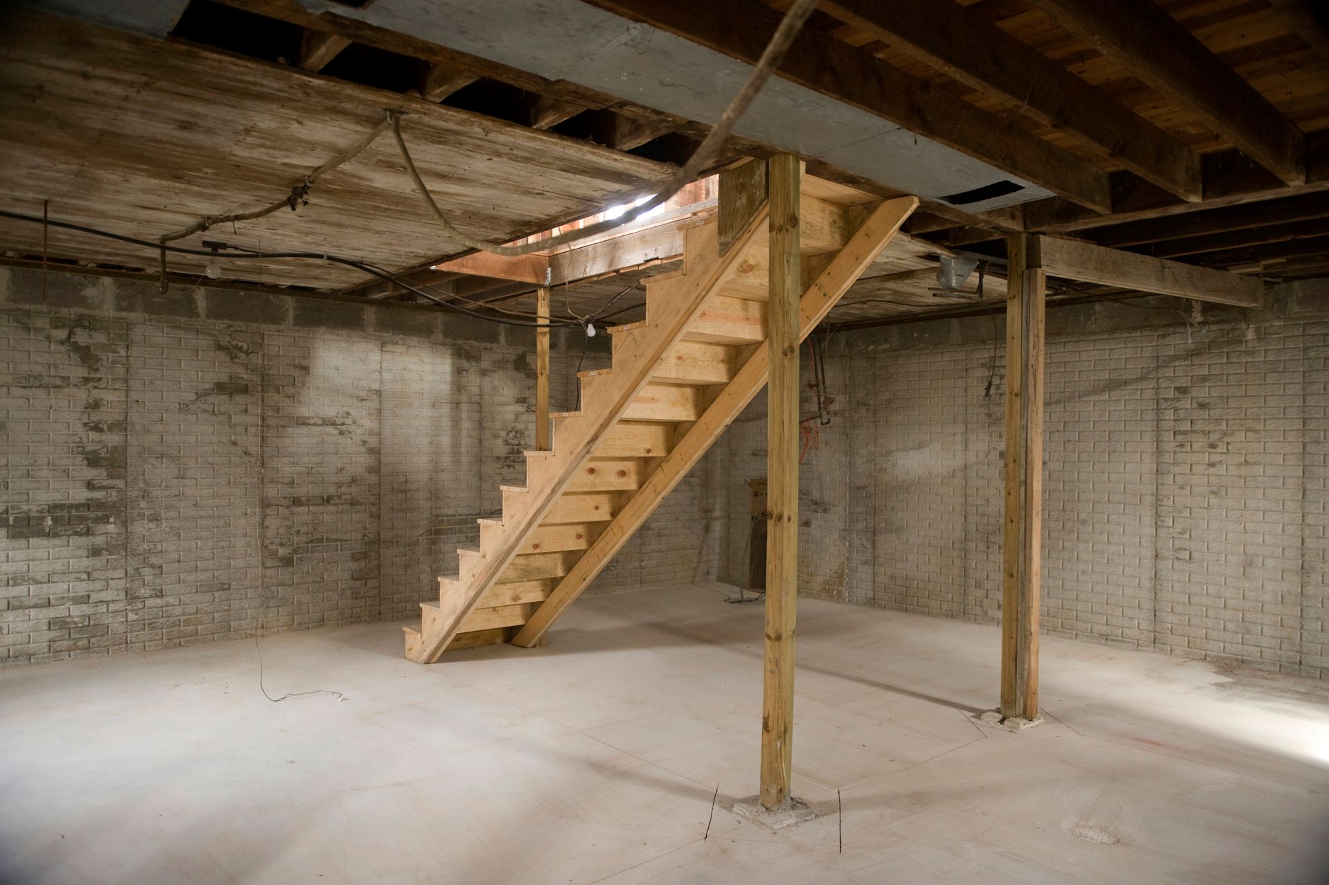 Basement with exposed beams, wooden staircase, and concrete walls and floor