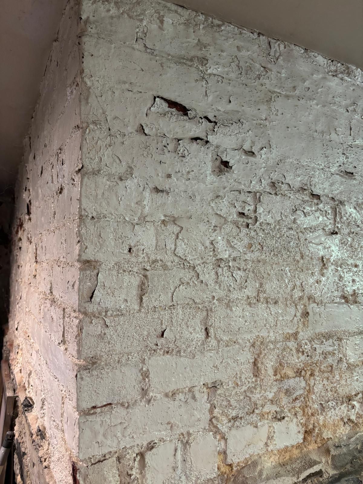White painted brick corner, with visible texture and some damage.
