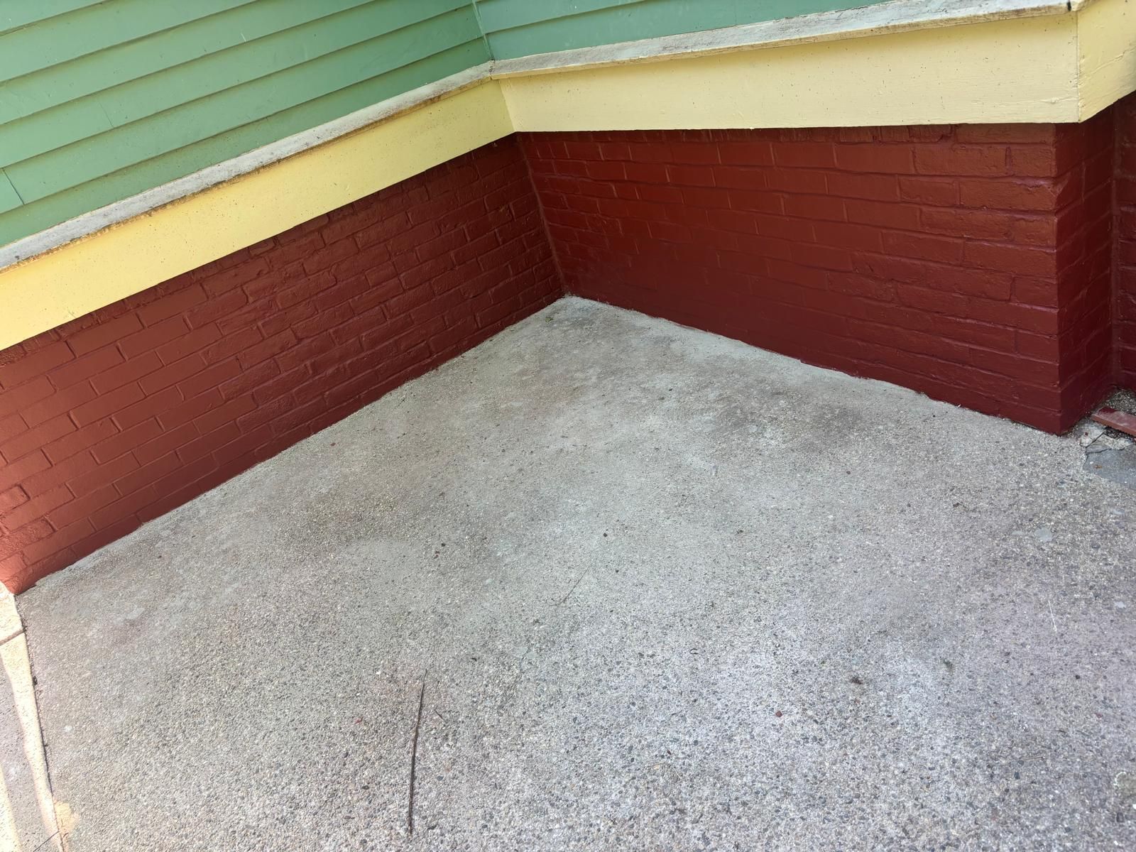 Red brick foundation and concrete floor under a green and yellow building exterior.