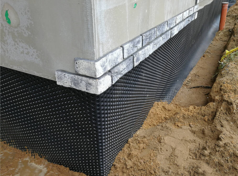 House foundation with black waterproof membrane and brick veneer under construction