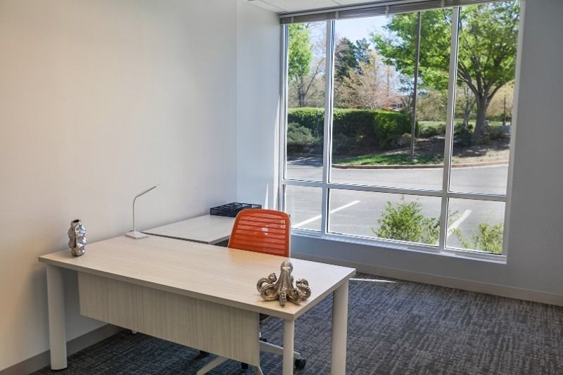 A small office with a desk and chair in front of a large window.