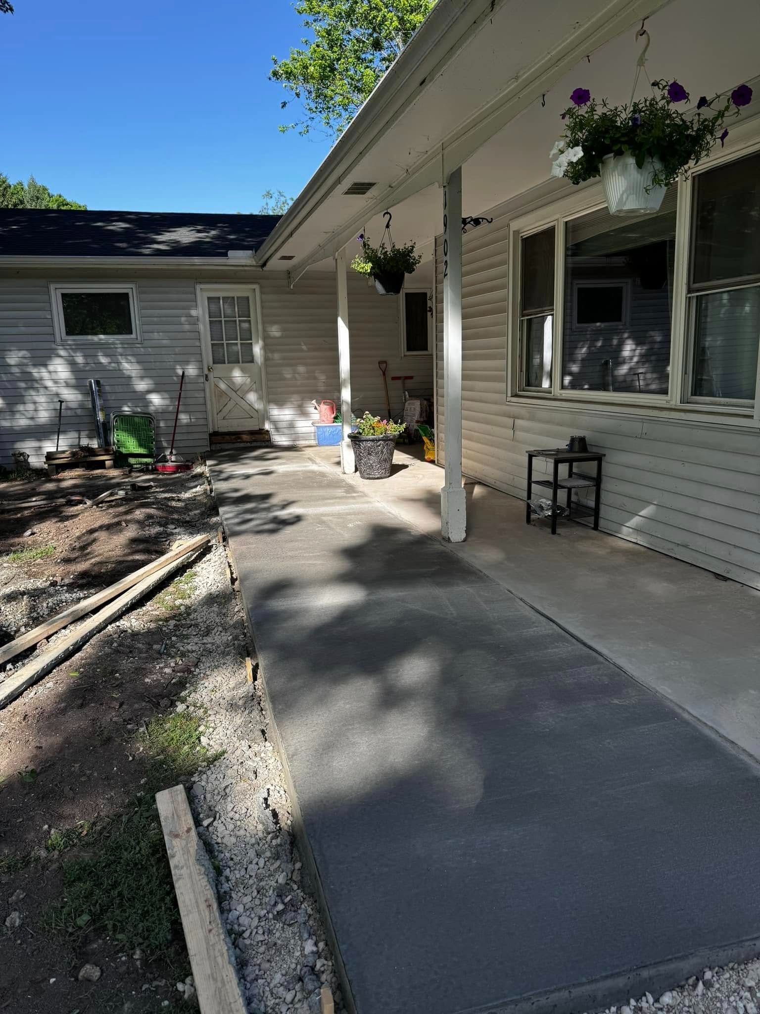 A house with a porch and a concrete walkway leading to it.