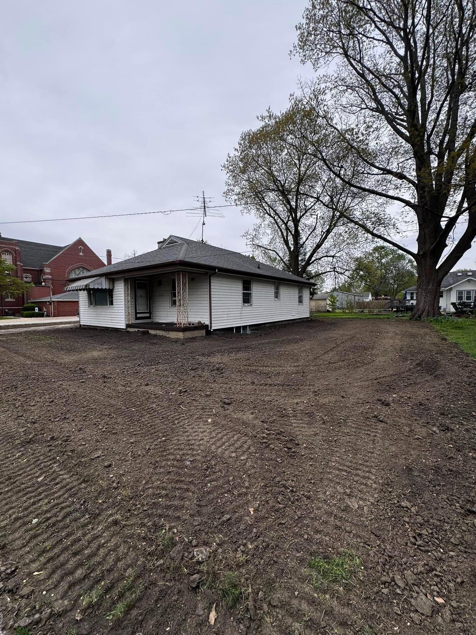 A white house is sitting in the middle of a dirt field.