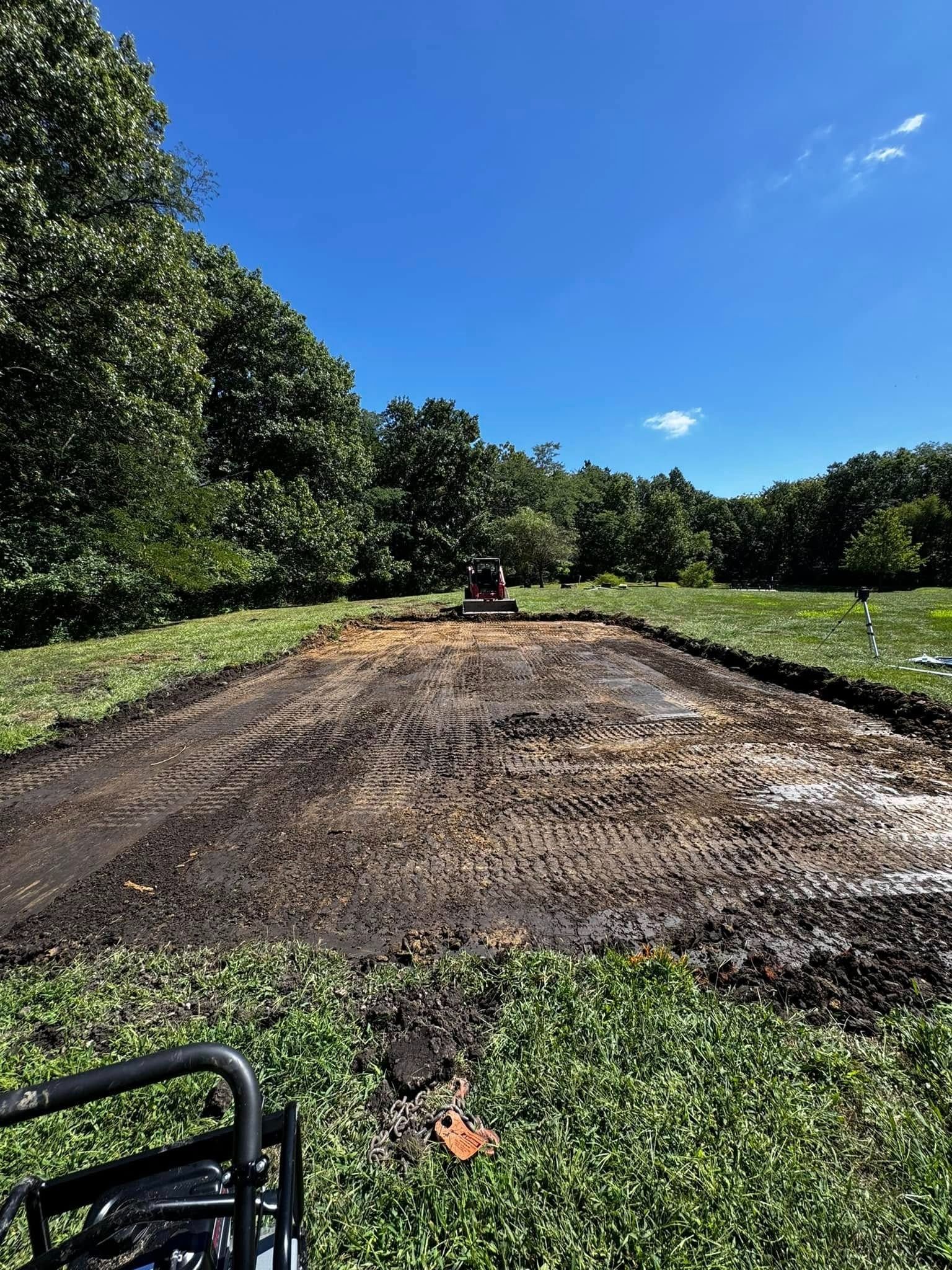 A tractor is driving down a dirt road in a field.