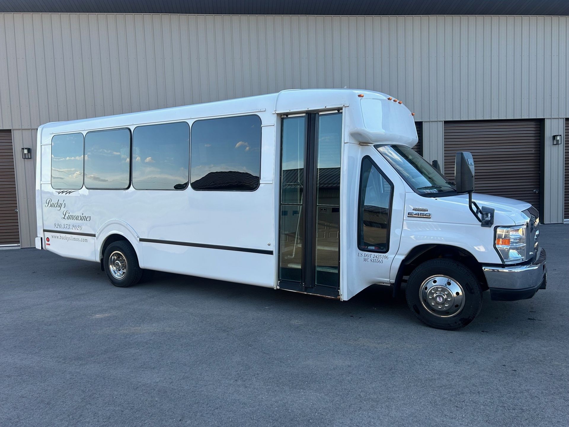 A white bus is parked in front of a building.