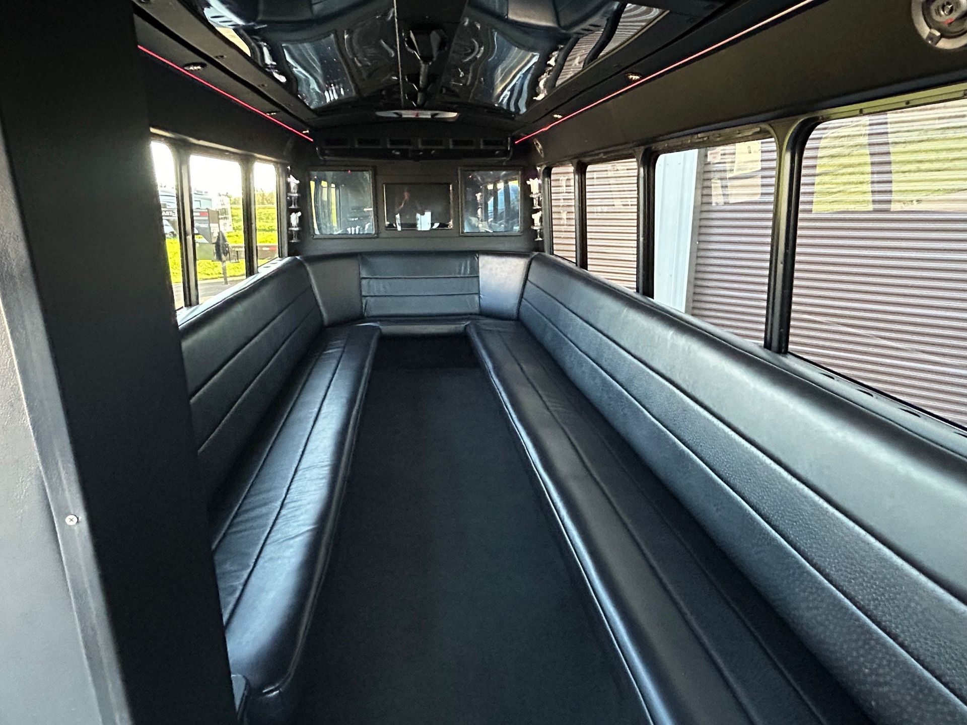 The inside of a bus with black seats and a lot of windows.