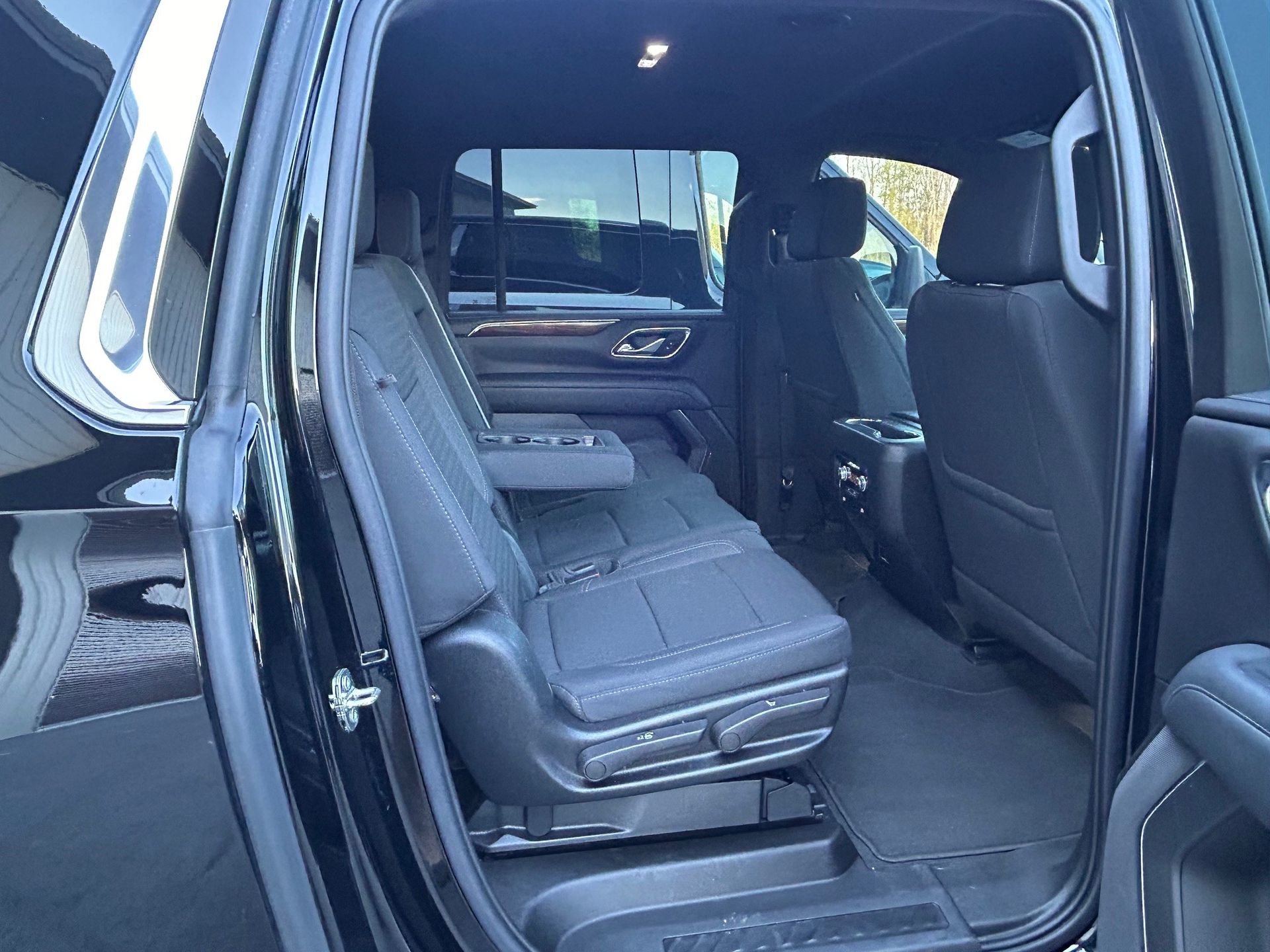 The back seat of a black truck with the door open.