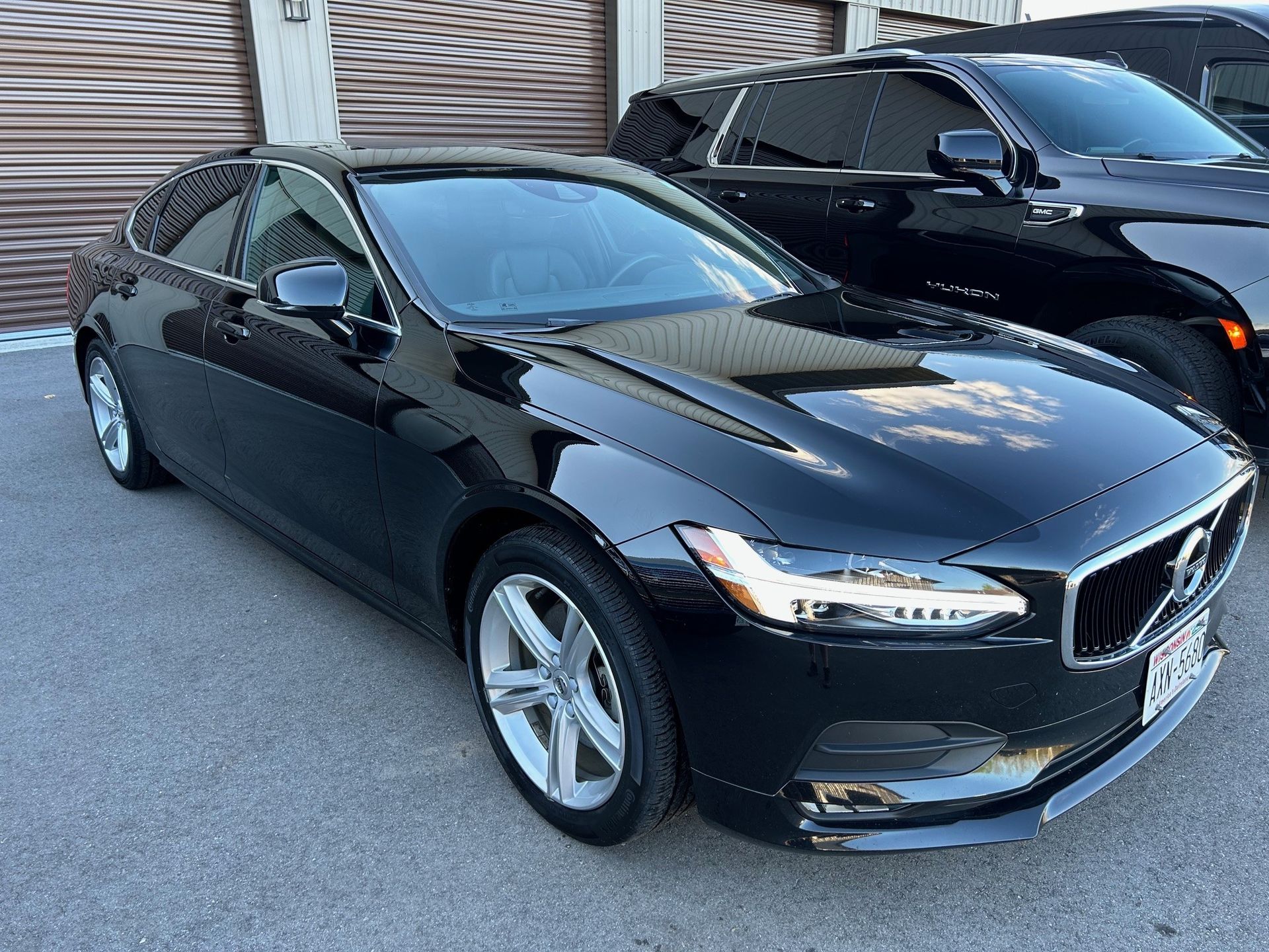 A black car is parked next to a black suv in front of a garage door.