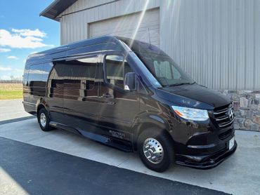 A black van is parked in front of a building.