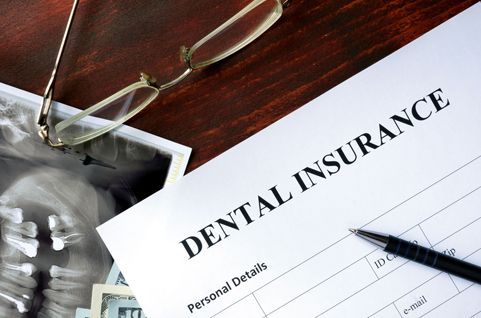 A dental insurance form is on a wooden table
