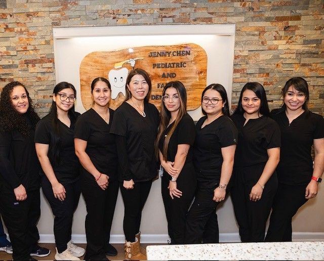 A group of women are posing for a picture in front of a sign that says sunny creek pediatric and family dentistry