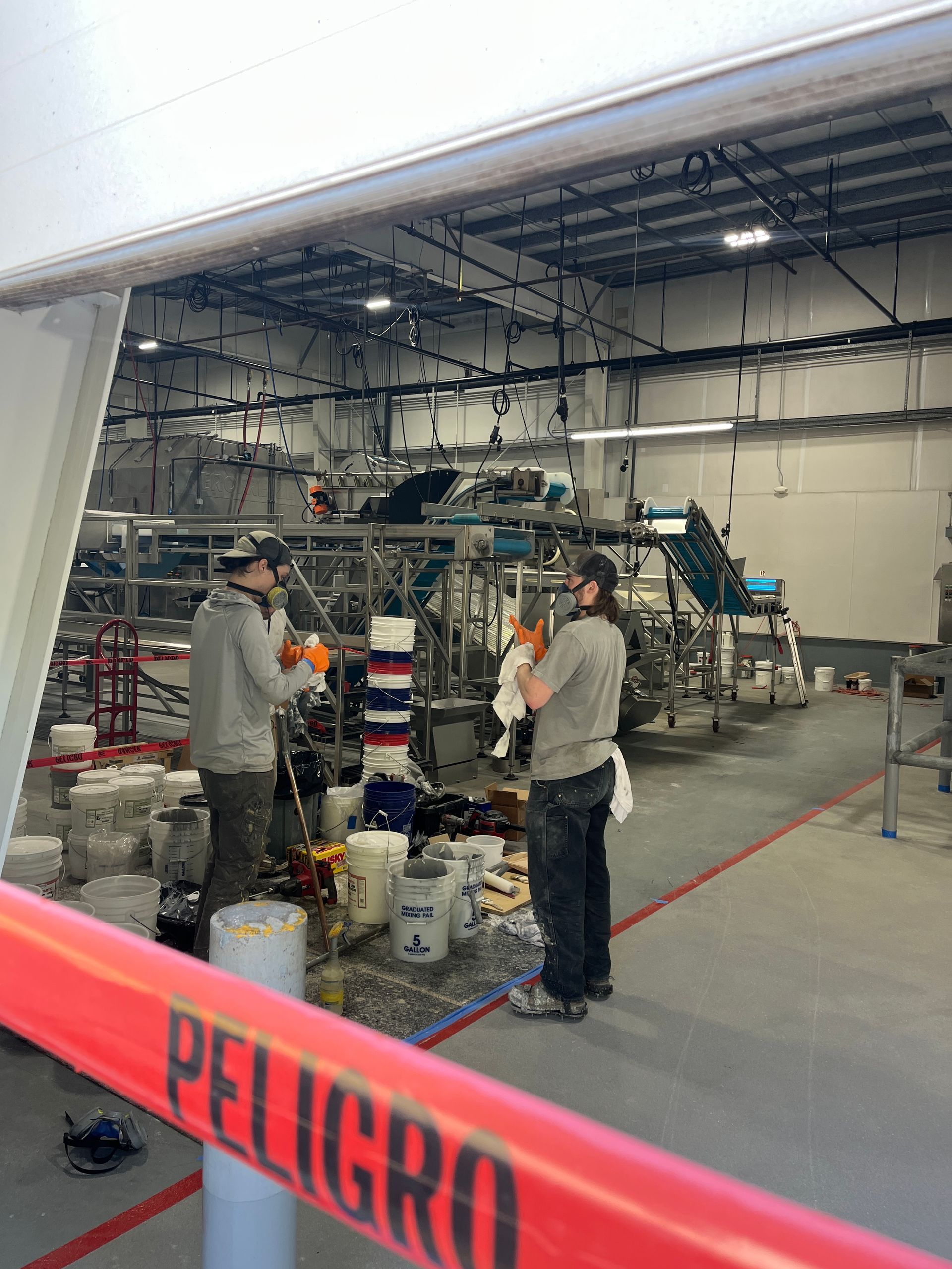 Two workers inside a warehouse, likely installing equipment, with a red 