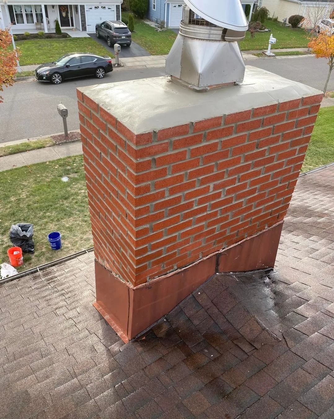 Brick chimney with copper flashing and a metal cap on a residential roof.