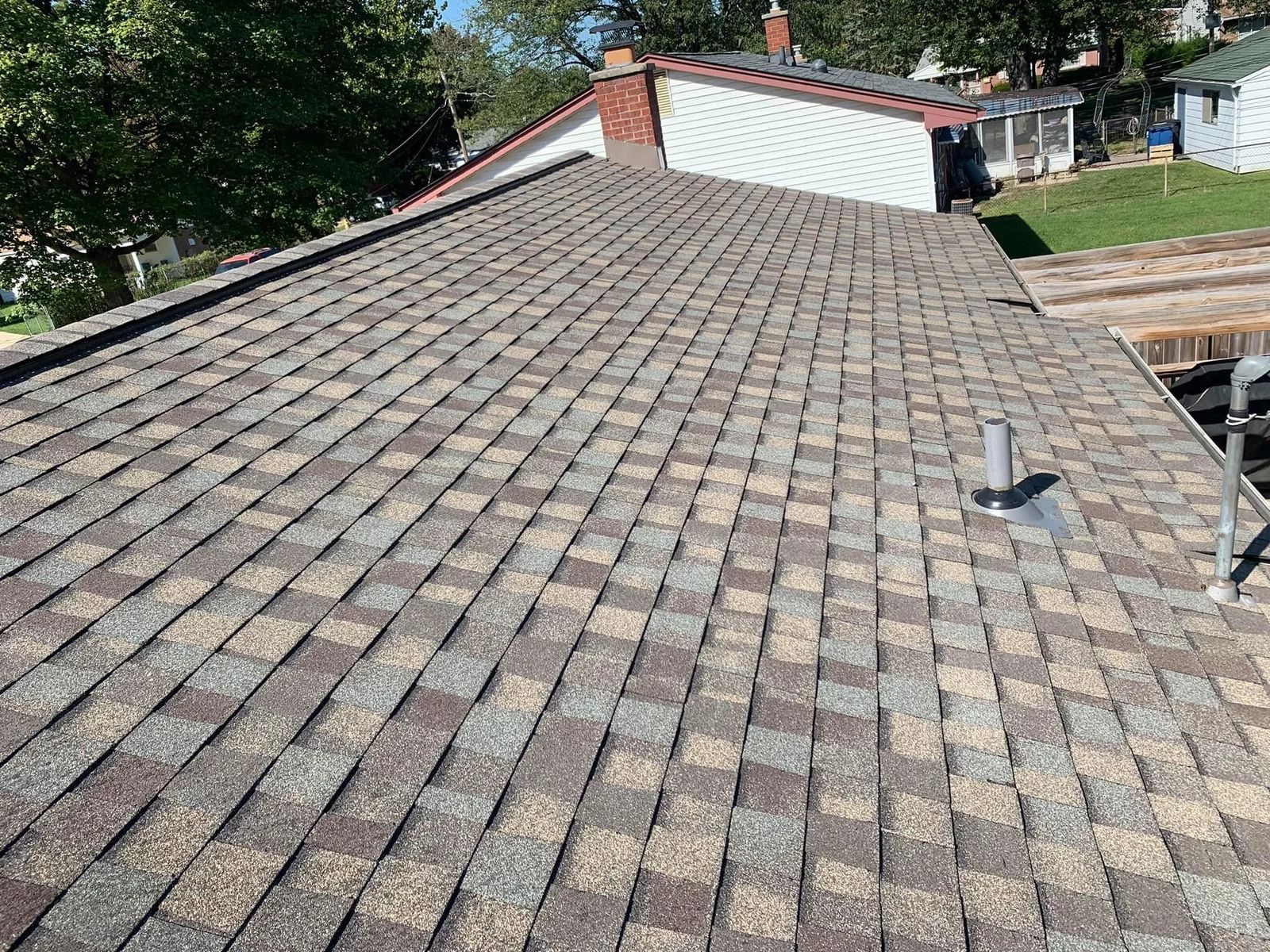 Overhead view of a shingled roof, brown and grey hues, on a sunny day.