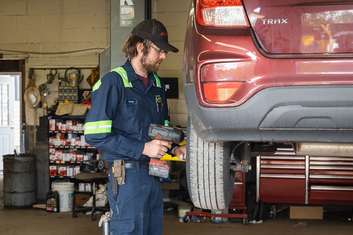 A man is working on a red car in a garage.