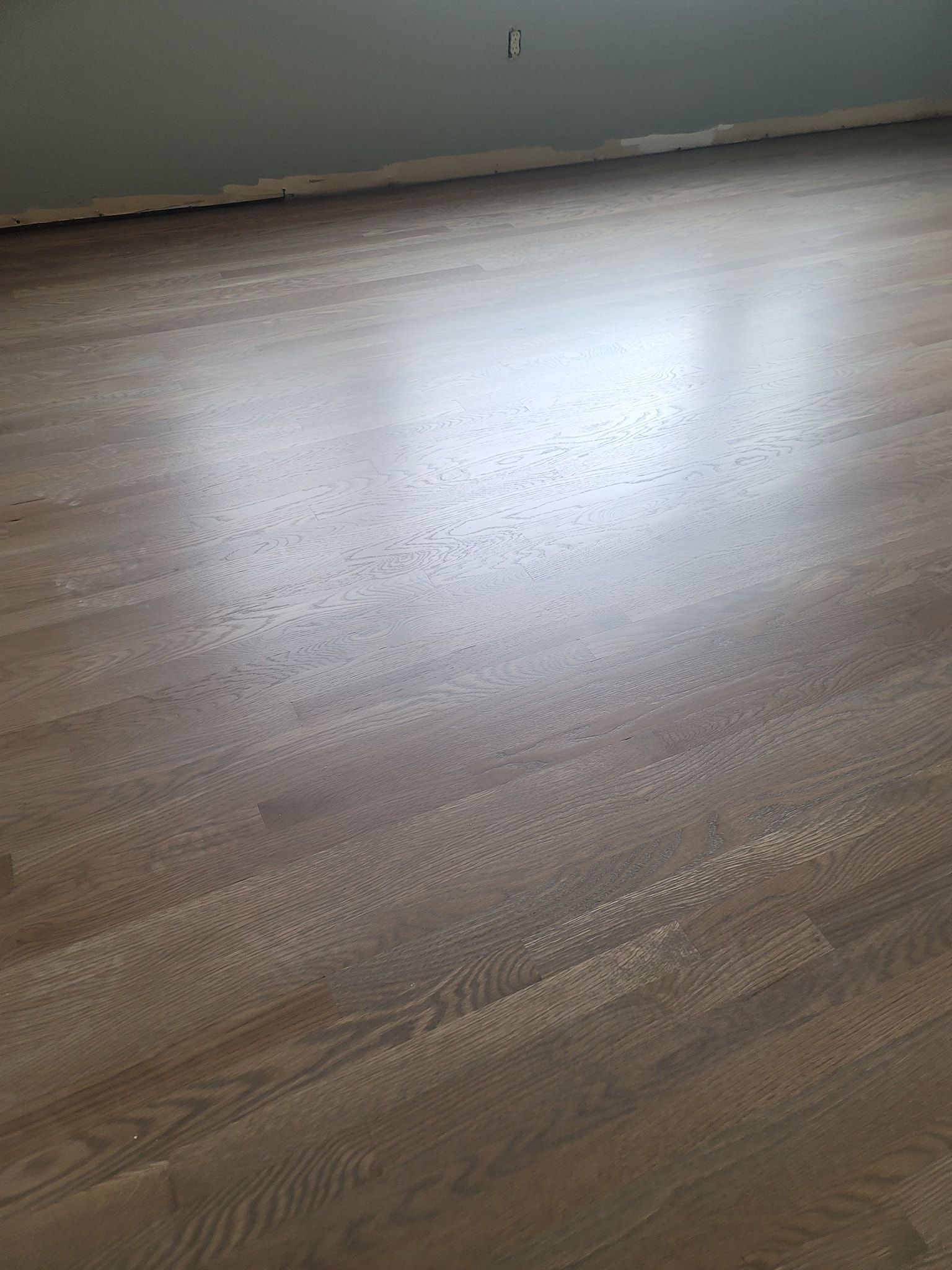 Wooden floor, light brown color, with visible grain, reflecting light, indoors.