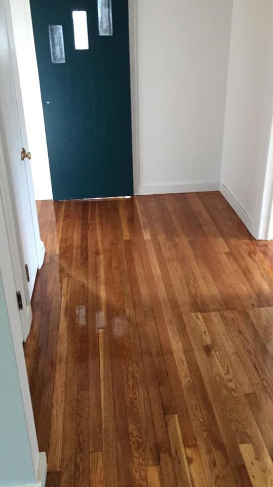 Wooden floor leading to a teal door with white trim, light shining through.