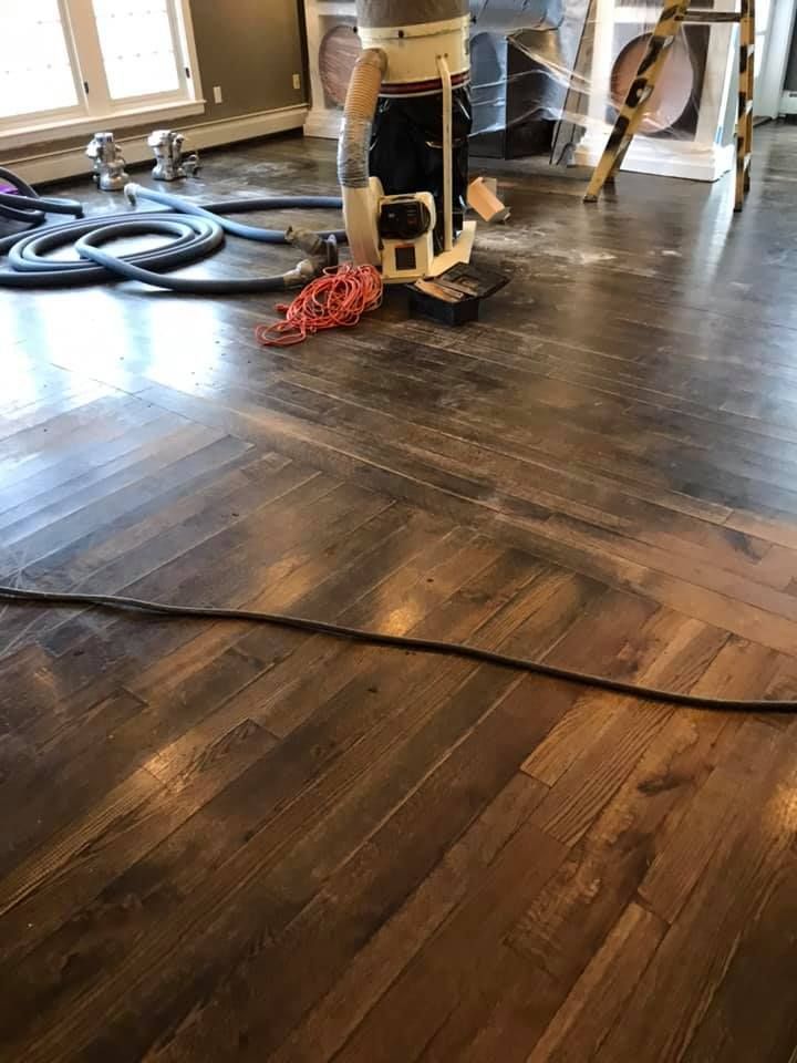 Hardwood floor being refinished with sanding machine; tools and supplies nearby.