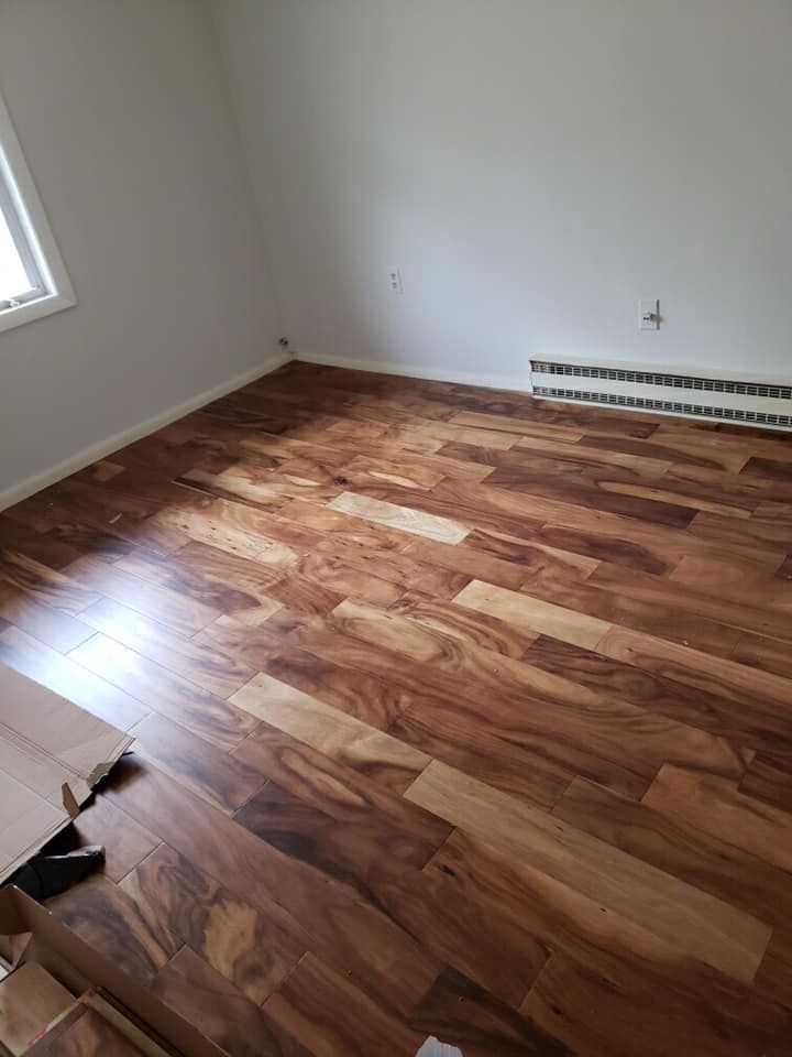 Newly installed hardwood floor in a room with white walls. A window is on the left; baseboard heater is on the right.