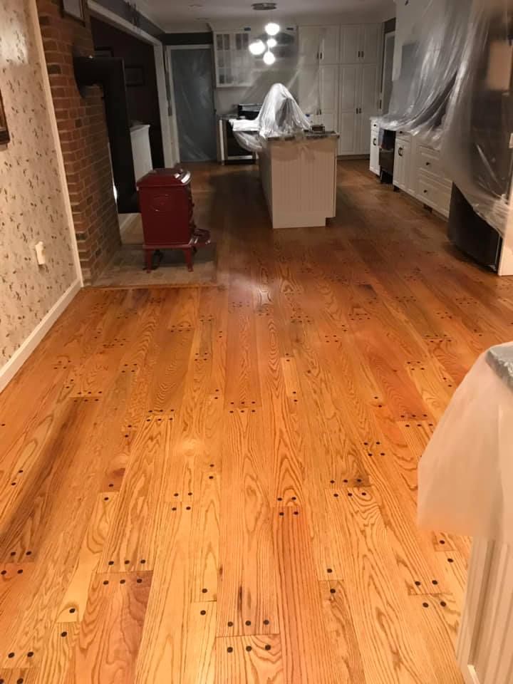 Newly refinished wood floors with nail holes, kitchen renovation in progress.