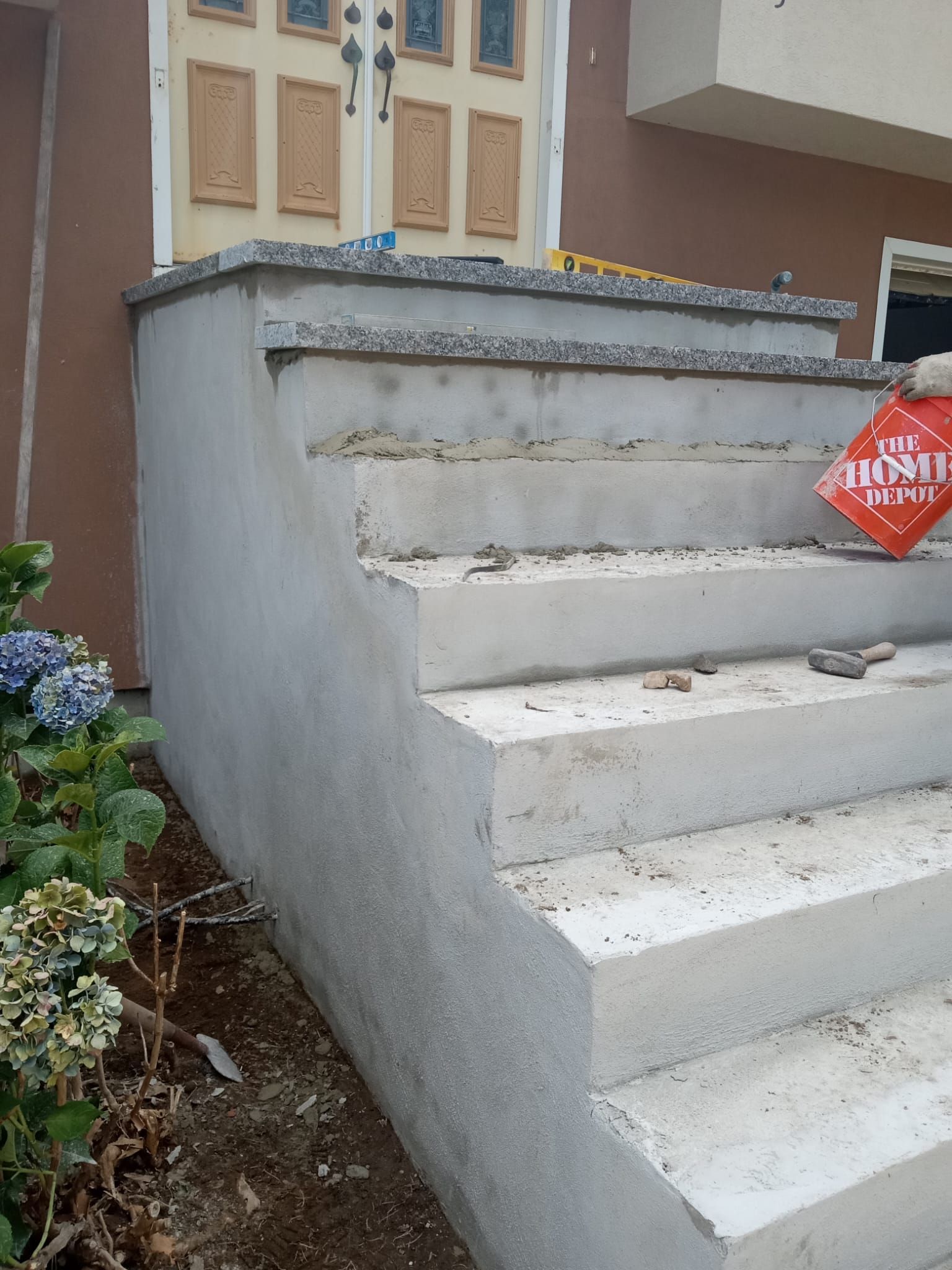 Concrete front steps being built outside a brown building with a double door entrance.