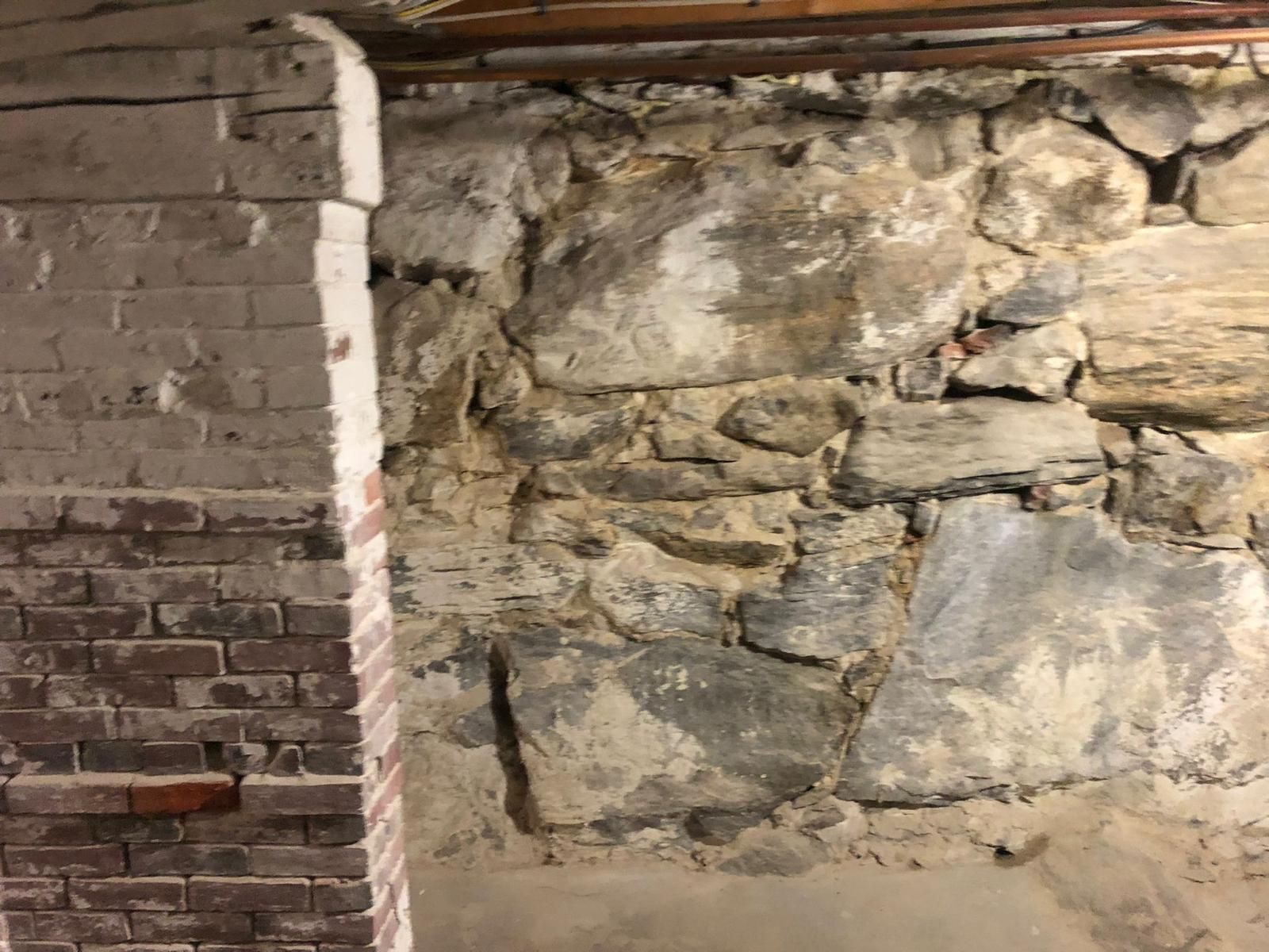 Stone foundation wall with brick column, showing age and mortar.