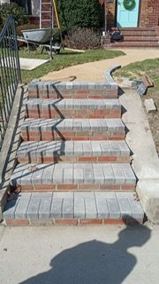 Brick steps leading up to a house with a pathway; light and shadows.