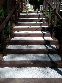 Wooden outdoor stairs with white gravel treads, flanked by brown railings.