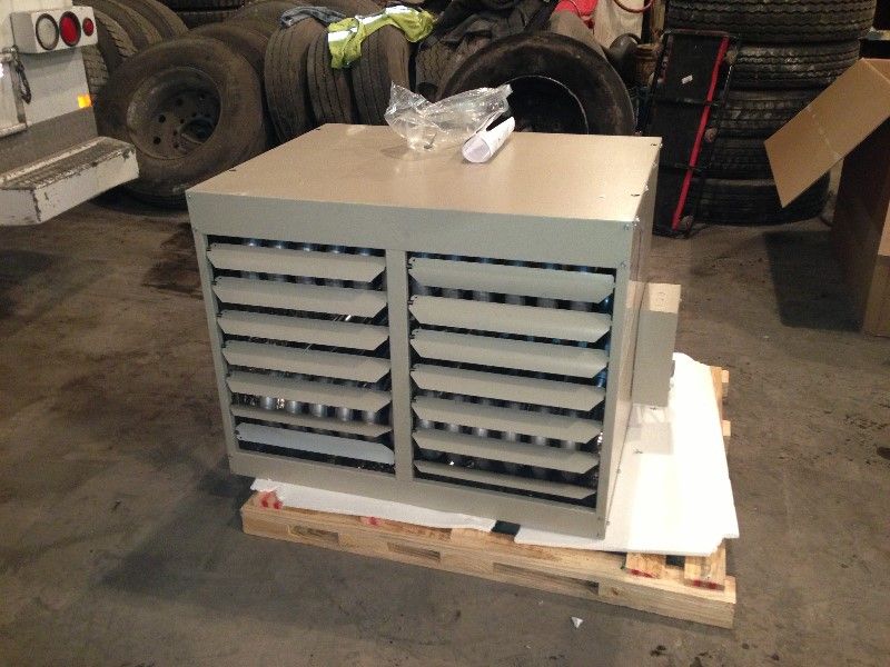 Gray metal cabinet with louvered vents on a wooden pallet in a garage or warehouse.