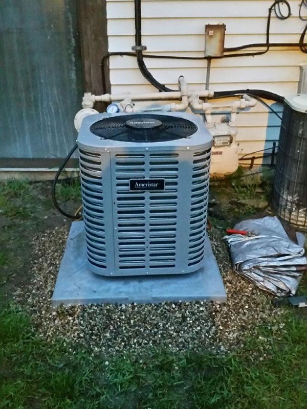 Outdoor air conditioner unit on a concrete pad beside a house wall.