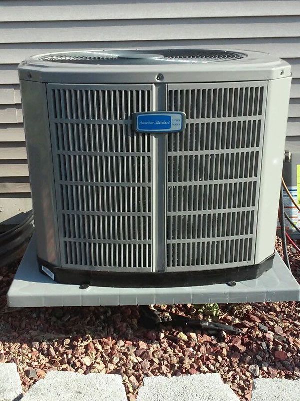 Outdoor central air conditioning unit on a concrete pad beside a house