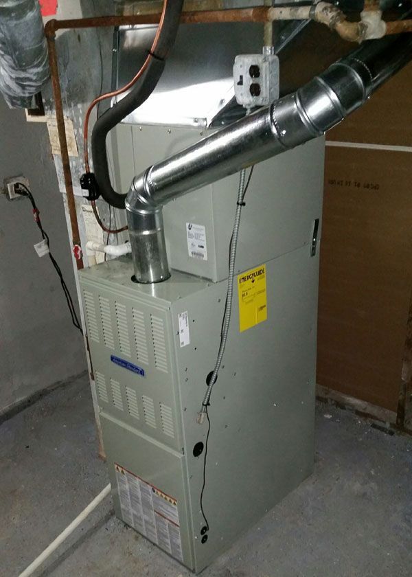 Gray furnace unit with metal ductwork in a basement utility room