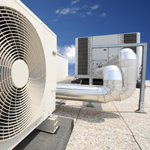 Rooftop HVAC units and silver ductwork on a gravel-covered industrial roof under a blue sky