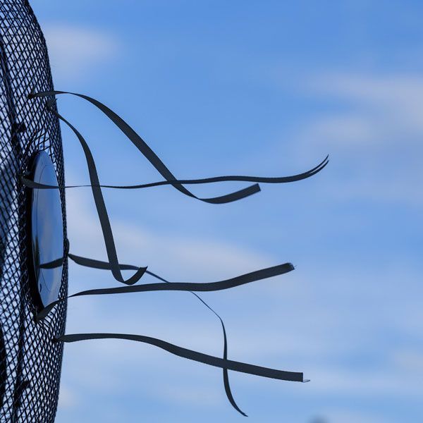 Frayed black wires on a metal fence against a blue sky