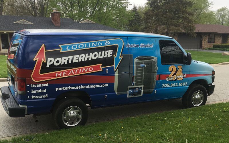 Blue Porterhouse Heating service van parked outdoors on a grassy residential street