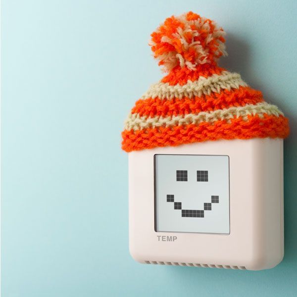 Small white thermometer with a pixel smiley face wearing an orange-and-cream knit hat against a light blue background
